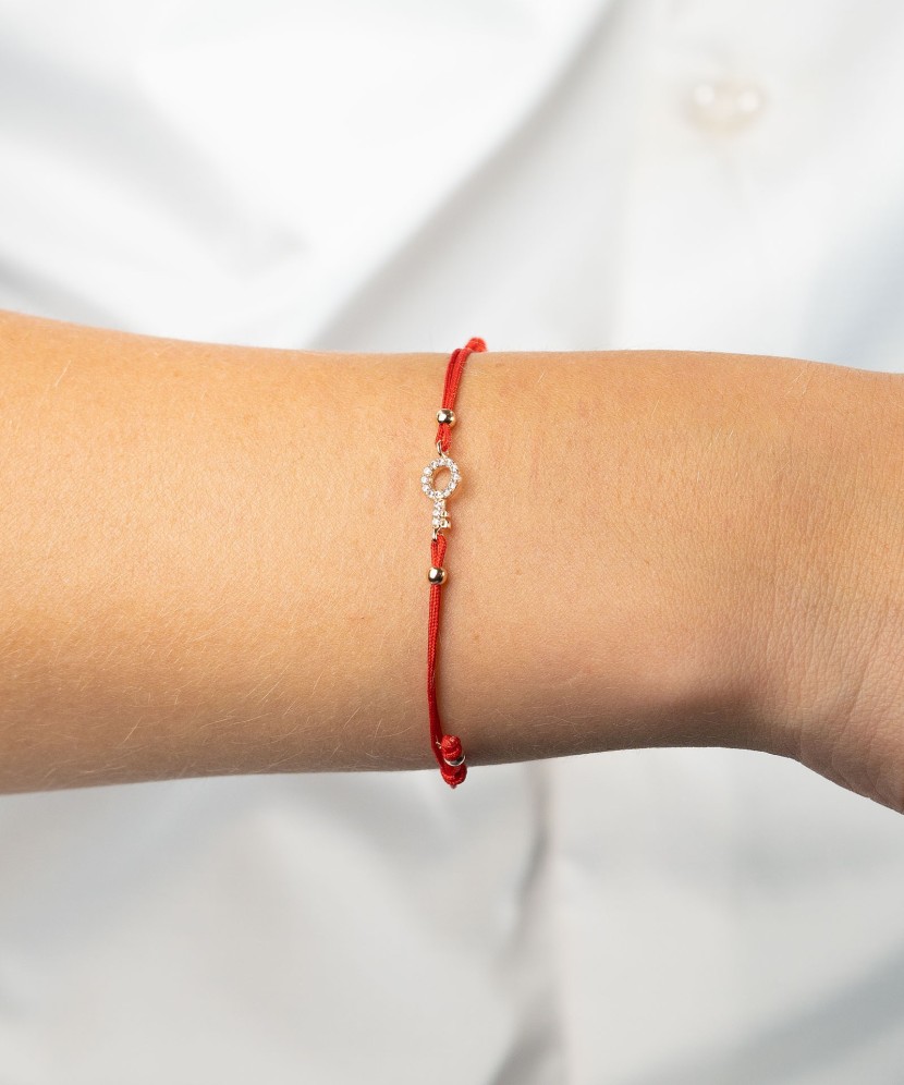 Red string bracelet with a gold pendant and zirconium